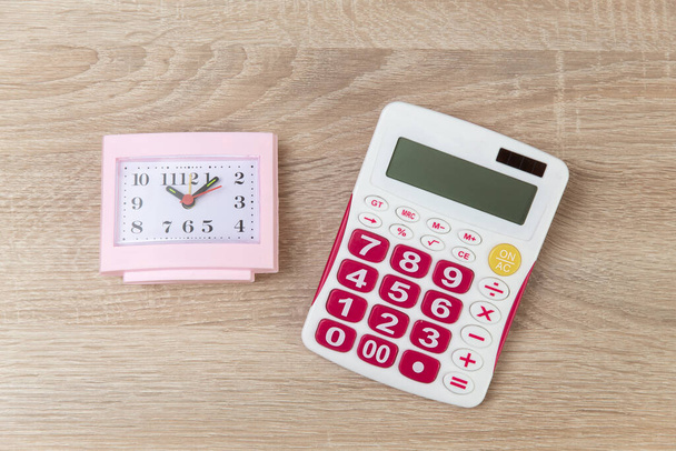 Square vaaleanpunainen herätyskello laskin puinen pöytä - Valokuva, kuva