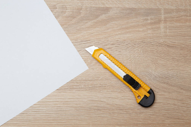 Papier i nóż do papieru na drewnianym stole - Zdjęcie, obraz