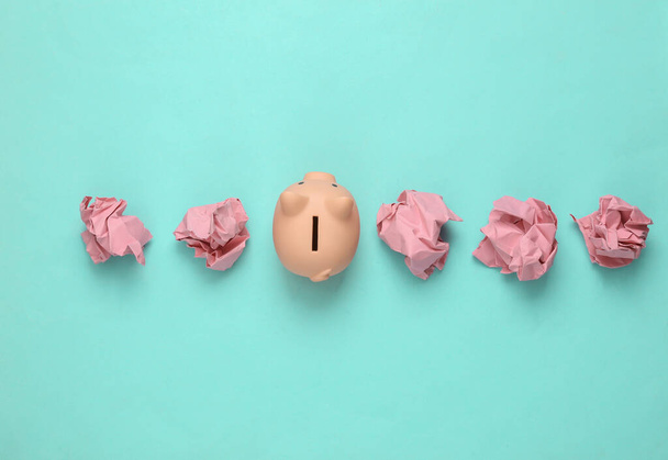 Piggy bank with crumpled paper balls on blue background - Photo, Image