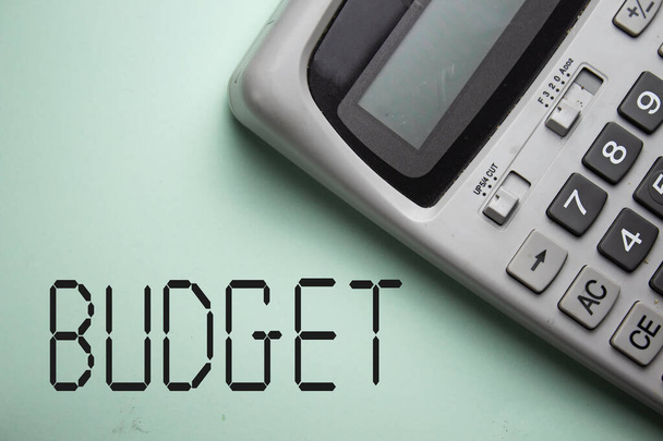 Havi költségvetési koncepció szürke kalkulátorral zöld háttérrel - Fotó, kép
