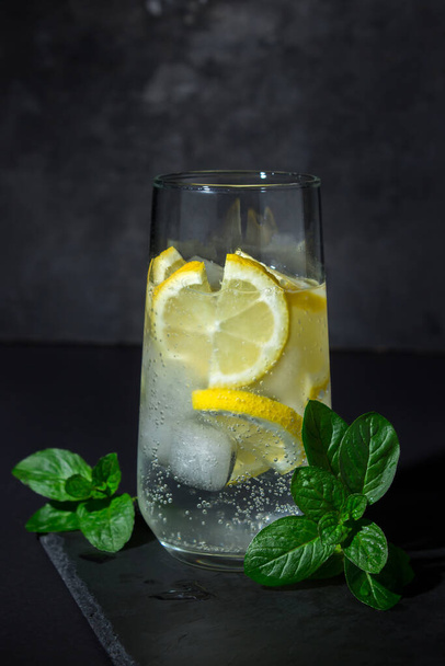 Refreshing cocktail on a black background. Soft drink with ice and lemon. cold drink - Fotoğraf, Görsel