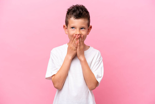 Μικρό καυκάσιο αγόρι απομονωμένο σε ροζ φόντο χαρούμενο και χαμογελαστό που καλύπτει το στόμα με τα χέρια - Φωτογραφία, εικόνα
