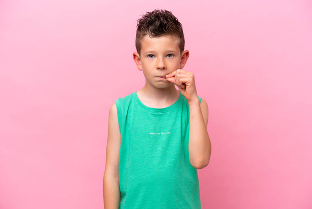 Pequeño chico caucásico aislado sobre fondo rosa mostrando un gesto de silencio - Foto, imagen