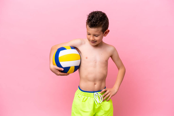Petit garçon caucasien jouant au volley isolé sur fond rose avec une expression heureuse - Photo, image