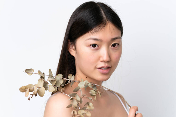 Young Chinese woman isolated on white background holding a eucalyptus branch. Close up portrait - Fotoğraf, Görsel
