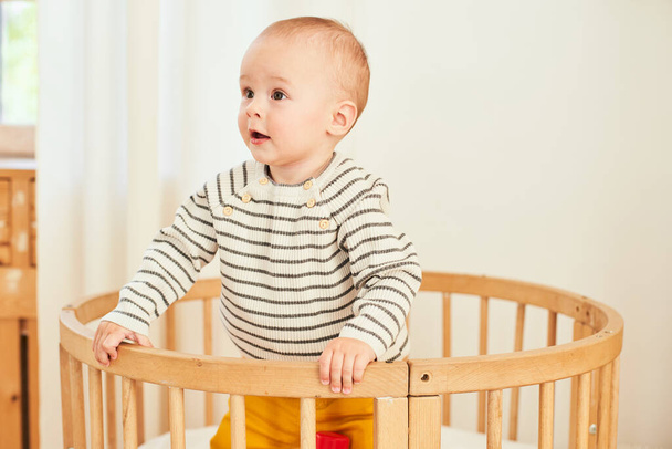 A cute little newborn baby in pajamas stands in a crib. The child and daytime sleep. Health care, infant sleep. Childhood concept. - Foto, Bild