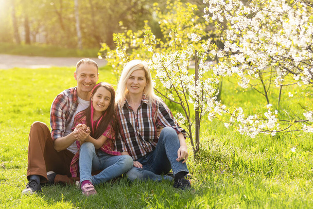 Счастливая семья проводит хорошее время вместе весной в цветочном саду. - Фото, изображение