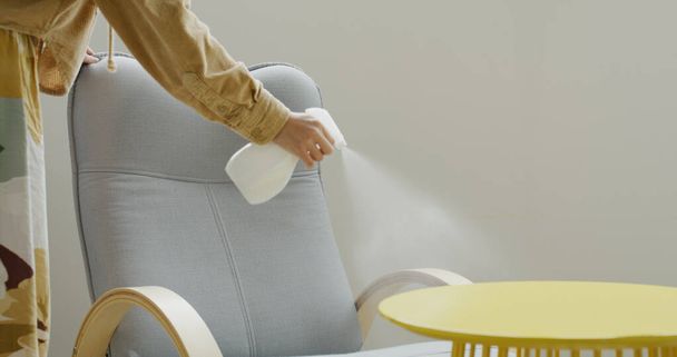 Donna utilizzare detergente spray per la pulizia della sedia a casa - Foto, immagini