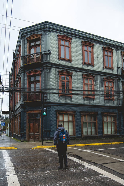 Backpacker přechod ulice a krásné zelené staré století tři uložené budovy s neoklasicistní architekturou, ozdoby a balkony v zataženo den, Valdivia, Chile - Fotografie, Obrázek