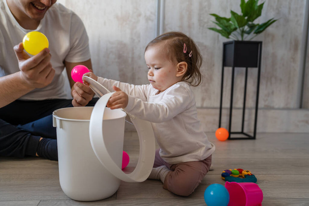 baby girl and her father young caucasian man with daughter playing at home happy sitting on the floor with toys in day fatherhood childhood family concept real people copy space - Photo, Image