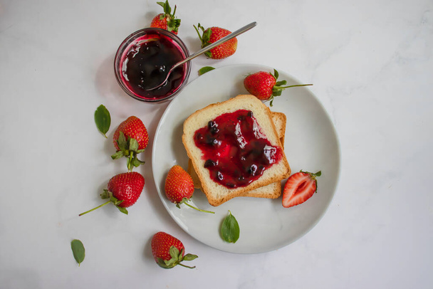 Strawberry jam in a glass of bread on an old background - Photo, Image