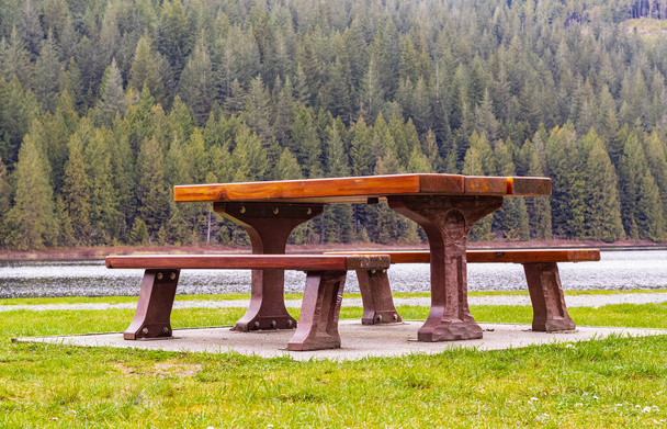 Wooden seat in a park. Picnic in the park. Rest in the open area. Wooden picnic table and seats. Street view, travel photo, nobody, selective focus - Foto, imagen