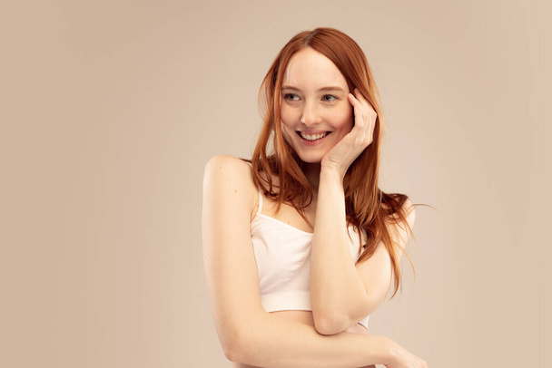Portrait of attractive young red-haired girl smiling, posing isolated over grey studio background. Tenderness. Concept of natural beauty, body and skin care, health, spa, wellness, cosmetics, ad - Foto, Bild