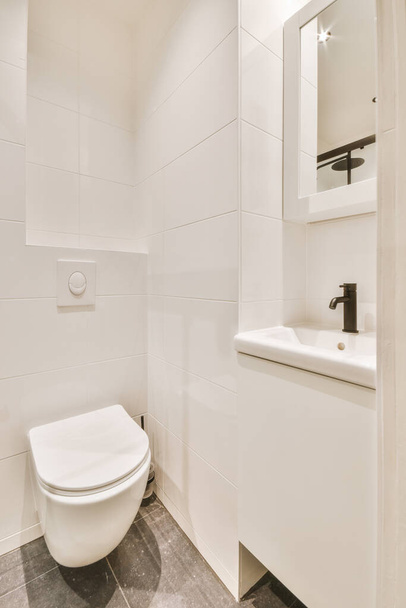 Falra akasztott WC és kis mosogató a sarokban WC-szobában bézs csempével - Fotó, kép