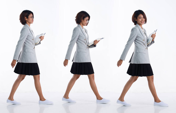 完全な長さ20代の若いアジアの女性教師の学生弁護士は、前方右左歩いて、ブレザースカートと靴を着用する。オフィスの女性は白い背景孤立した上の本のフォルダを運ぶ - 写真・画像