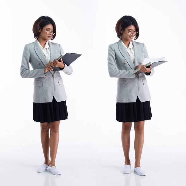 20-летняя студентка-азиатка, студентка-юрист, надевает юбку-блейзер, смотрит на работу. Офис женщина нести книги папки счастливая улыбка на белом фоне изолированы - Фото, изображение