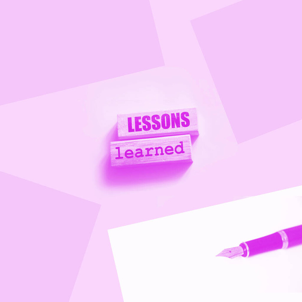 Bloques de madera con texto Lecciones aprendidas sobre fondo rosa. Concepto de educación empresarial. - Foto, imagen