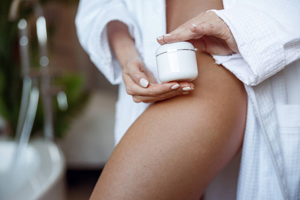 Close up of Caucasian female holding anti-cellulite cream and showing smooth leg. High quality photo - Zdjęcie, obraz