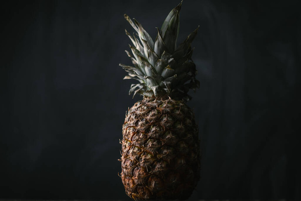whole ripe pineapple on black background. Juicy fruit. Close up shot - Fotó, kép