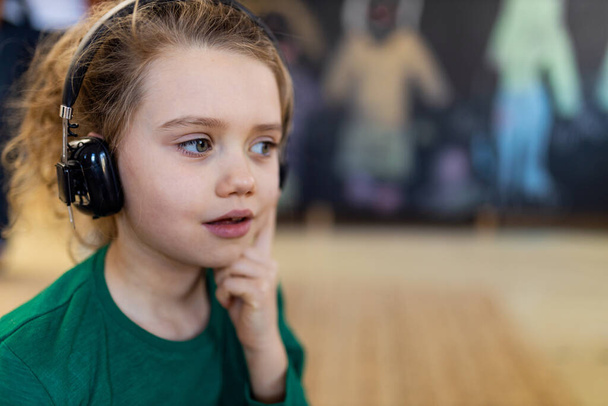 A little girl with headphones and microphone listening music, having fun and playing at home. - Foto, Imagen