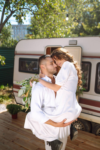 Beautiful wedding couple laugh and kiss relaxing in rv, camping in a trailer. Romantic moment. Together. Wedding. Marriage. - Fotó, kép