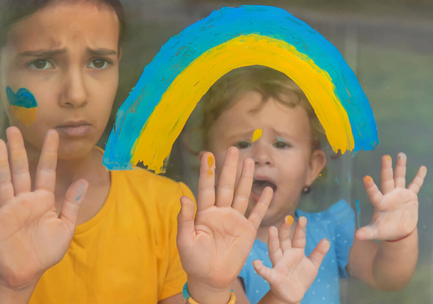 窓の上の子供たちは虹のウクライナの平和な空を描いた。選択的フォーカス。キッド. - 写真・画像