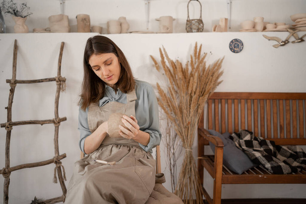 woman artist sculpts from wet clay in studio. ceramist makes handicrafts from ceramics. female industriousness concept. copy space. - Fotografie, Obrázek