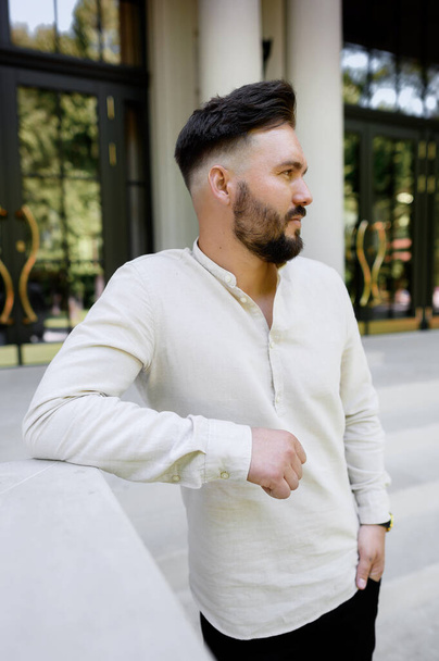 Handsome young guy with a bearded man in a linen shirt on the background of the house - Foto, imagen