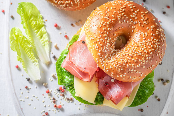 Tasty and spring bagel with cheese and prosciutto. Bagels as fresh sandwich with vegetables. - Foto, Imagem