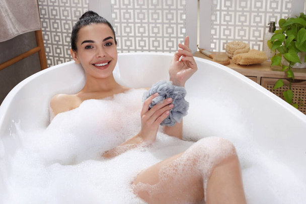 Woman taking bath with mesh pouf indoors - Zdjęcie, obraz