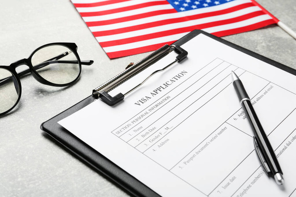 Visa application form, glasses and American flag on light grey table, closeup - Photo, image