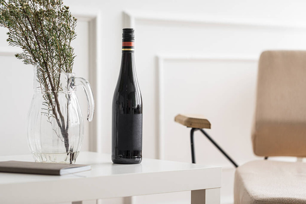 Bottle of wine and vase on white coffee table - Φωτογραφία, εικόνα