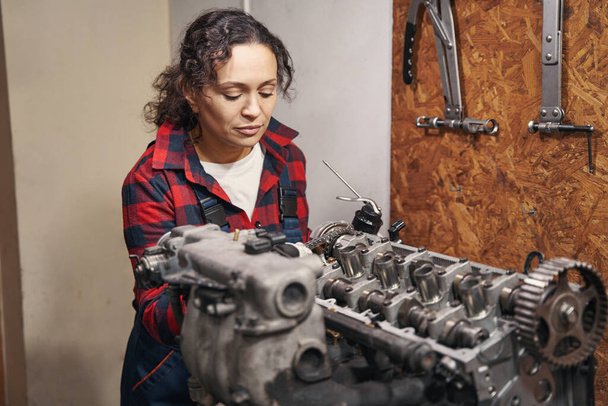 Female vehicle technician repairing car motor in automobile repair garage - Фото, зображення