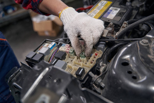 Close up of female technician hand in work gloves inspecting automobile components in vehicle garage - Fotografie, Obrázek