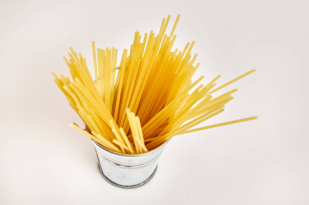 Miniatureimer aus Metall, gefüllt mit Spaghetti auf weißem Hintergrund. - Foto, Bild