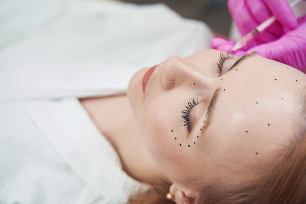 Retrato de vista superior de la mujer es alisado de la cara imitar arrugas en clínica de belleza - Foto, Imagen