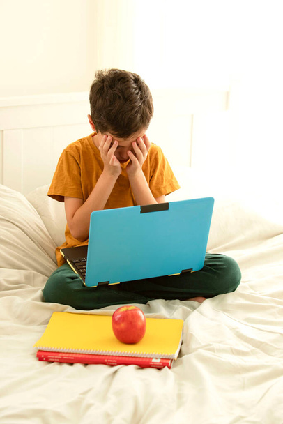 Criança triste com laptop, sentada na cama cobrindo seu rosto com as mãos. Conceito de cyberbullying, problemas de aprendizagem, comunicação online, lição de casa, psicologia infantil, saúde mental, digital, crianças - Foto, Imagem