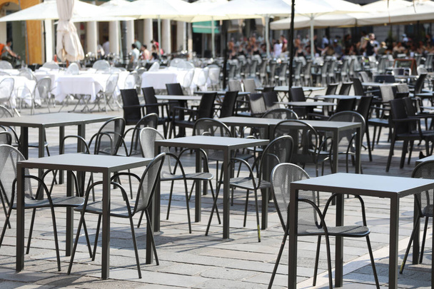 κενές καρέκλες και τραπέζια χωρίς πελάτες στο εστιατόριο alfresco στην πλατεία της ευρωπαϊκής πόλης κατά τη διάρκεια του αποκλεισμού - Φωτογραφία, εικόνα