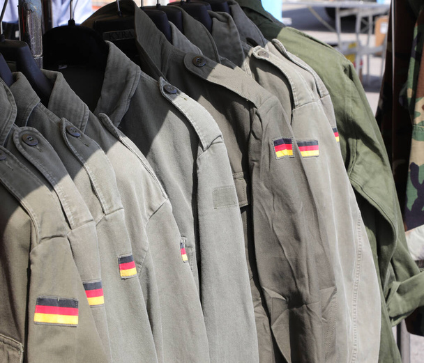 chaquetas verdes militares usadas con la bandera del ejército alemán para la venta en el puesto de ropa usada - Foto, Imagen