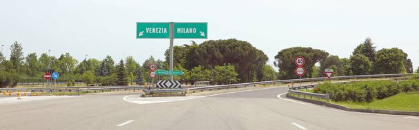 afslag autosnelweg met de Italiaanse aanduiding voor de stad VENICE aan de linkerkant of MILAN als u rechtsaf slaat zonder auto 's - Foto, afbeelding