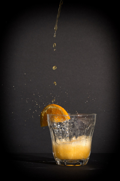 Orange flavoured soft drink splashing over the glass. - 写真・画像