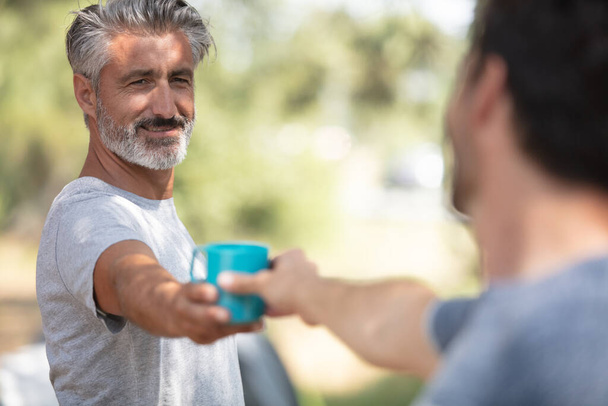 men with cup of morning coffee walking in park - Photo, image