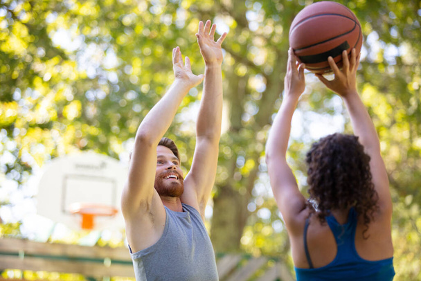 man and woman practicing basketball on outdoor court - Foto, afbeelding