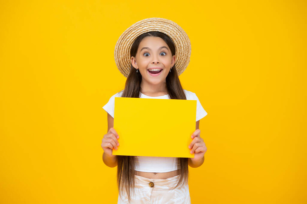 shocked teen girl hold empty advertisement paper with copy space on yellow background. - Foto, Imagem