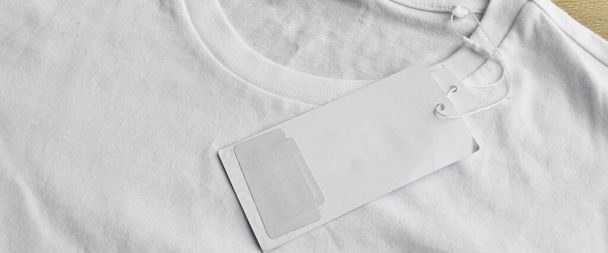 White clean blue t-shirt and blank empty label, on wooden floor - Valokuva, kuva