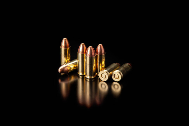 Pistol cartridges 9 mm on a smooth glossy surface with reflections. Ammunition for pistols and PCC carbines on a dark background. - Foto, immagini