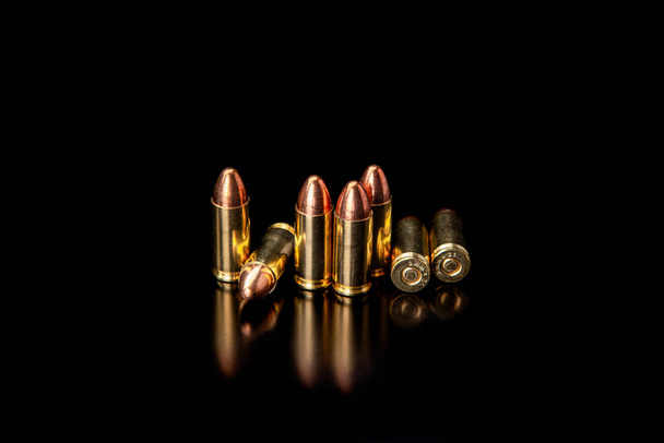 Pistol cartridges 9 mm on a smooth glossy surface with reflections. Ammunition for pistols and PCC carbines on a dark background. - Фото, изображение