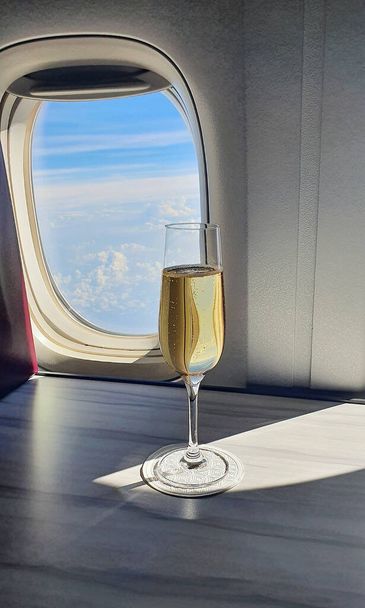 飛行機の窓の近くにシャンパンのガラスが  - 写真・画像