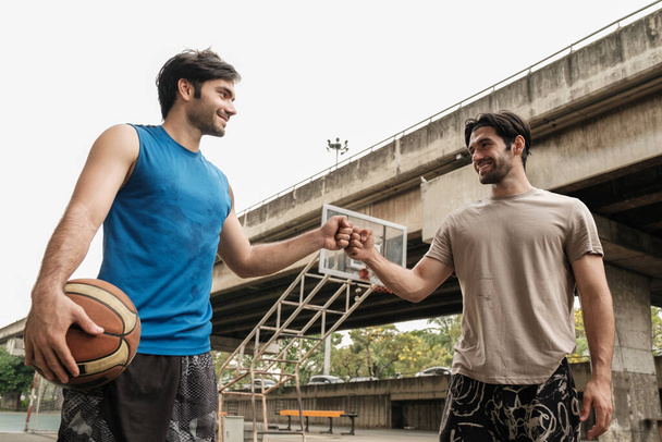 Zwei kaukasische Männer praktizieren Baskegball vor Gericht an der Stadtstraße. - Foto, Bild