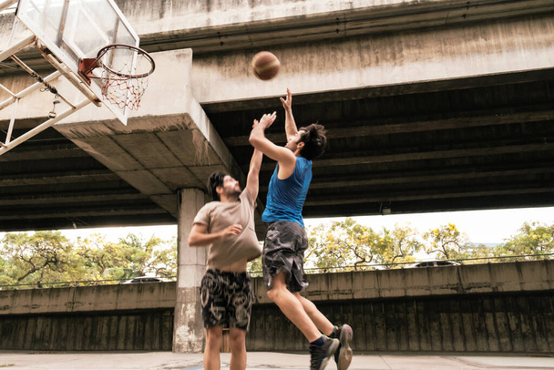 二人の白人男性練習バスケットボールで裁判所で都市部の通り. - 写真・画像